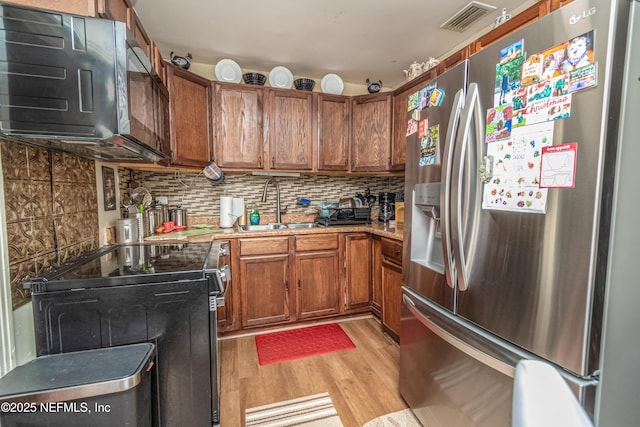 5545 Silverdale Ave, Jacksonville, FL 32209 - kitchen featuring a sink, light wood-style floors, brown cabinetry, visible vents, and black appliances
