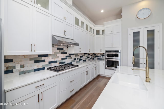 742 Honey Blossom Rd, Saint Johns, FL 32259 - kitchen featuring decorative backsplash, white cabinetry, under cabinet range hood, a sink, and appliances with stainless steel finishes