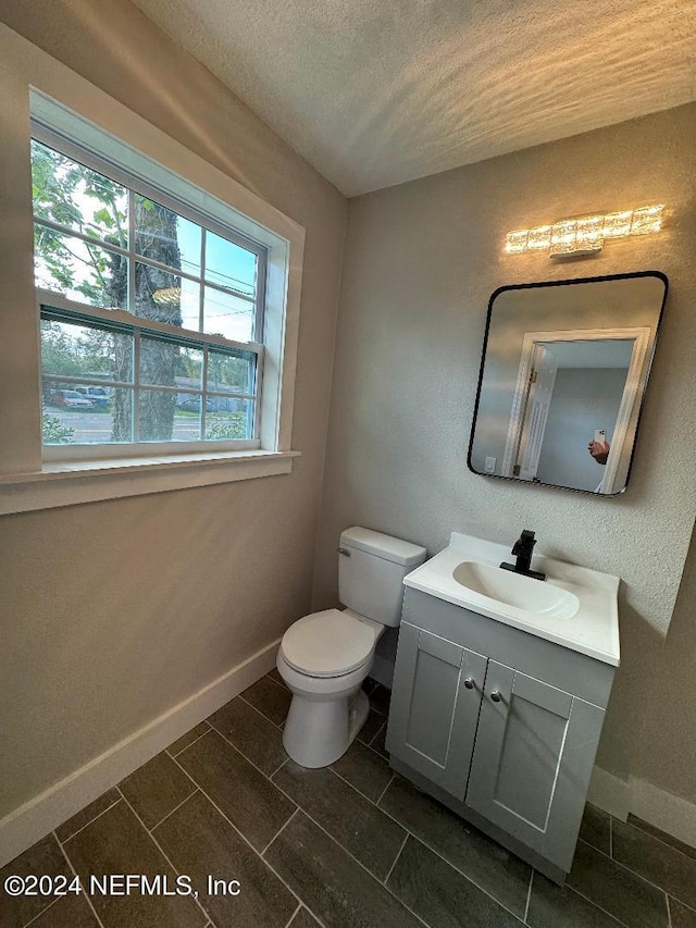 2535 Rogero Rd, Jacksonville, FL 32211 - half bath with baseboards, a textured ceiling, toilet, and vanity