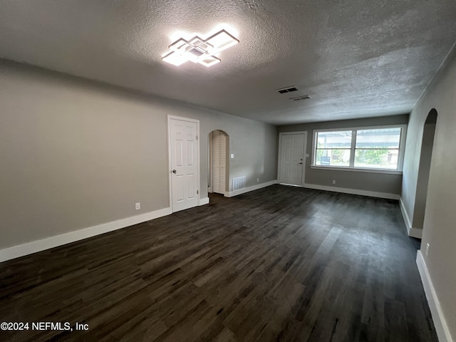 2535 Rogero Rd, Jacksonville, FL 32211 - spare room with arched walkways, a textured ceiling, baseboards, and dark wood-type flooring