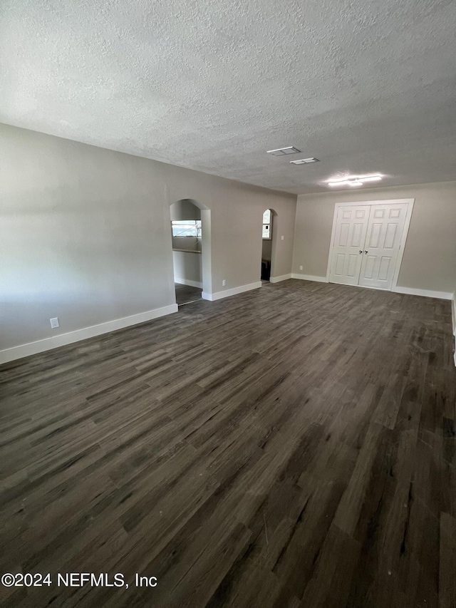 2535 Rogero Rd, Jacksonville, FL 32211 - interior space featuring arched walkways, baseboards, dark wood-style flooring, and a textured ceiling