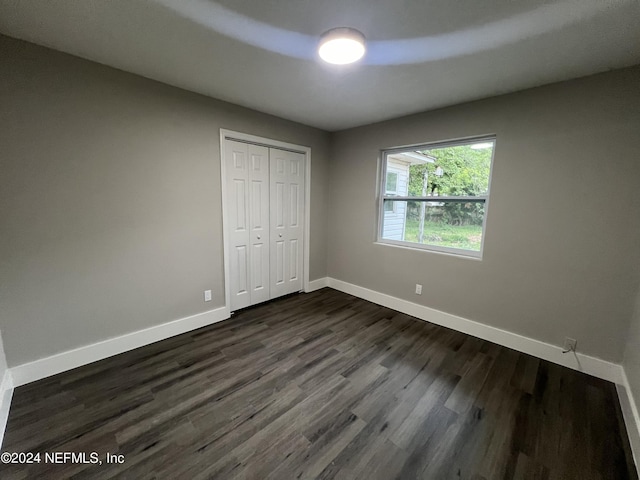 2535 Rogero Rd, Jacksonville, FL 32211 - unfurnished bedroom with baseboards, dark wood finished floors, and a closet