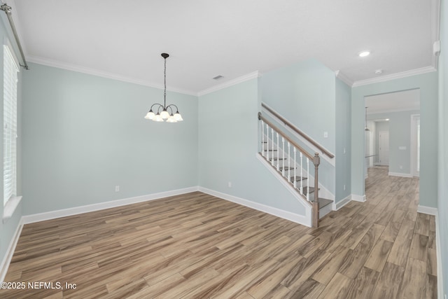 spare room with baseboards, an inviting chandelier, ornamental molding, and light wood finished floors
