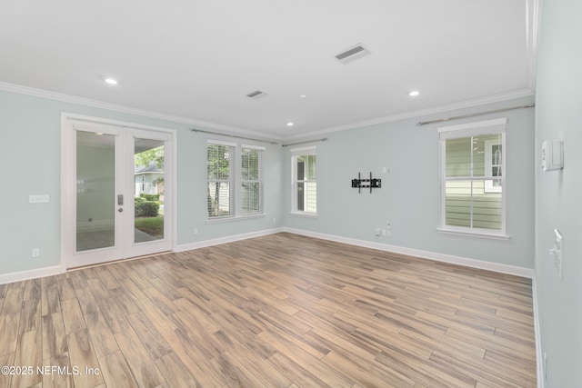 spare room with baseboards, ornamental molding, and light wood finished floors