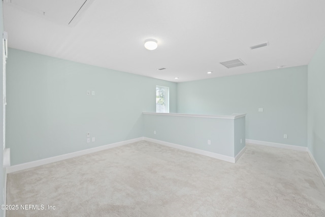carpeted empty room with baseboards, visible vents, and attic access