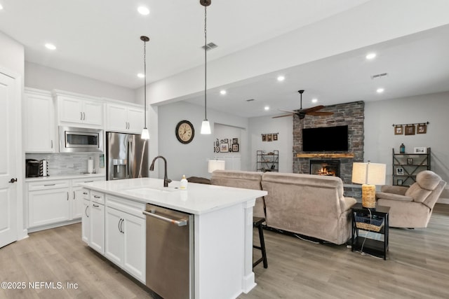 85325 Champlain Dr, Fernandina Beach, FL 32034 - kitchen with appliances with stainless steel finishes, a sink, ceiling fan, a fireplace, and light wood-type flooring