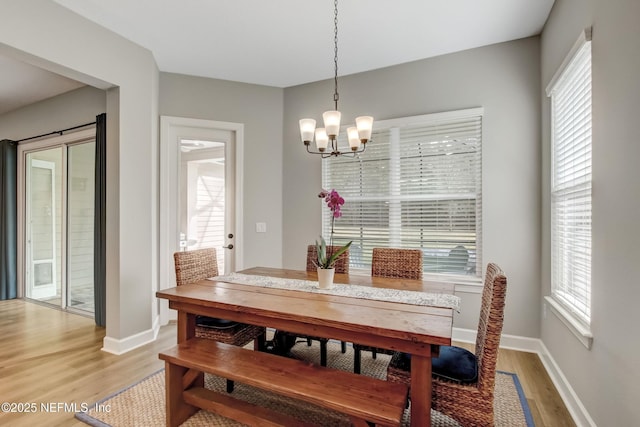 85325 Champlain Dr, Fernandina Beach, FL 32034 - dining area featuring a chandelier, light wood-style floors, plenty of natural light, and baseboards