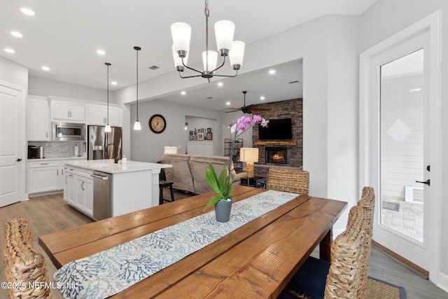 85325 Champlain Dr, Fernandina Beach, FL 32034 - dining room with light wood-style floors, ceiling fan, recessed lighting, a fireplace, and a chandelier