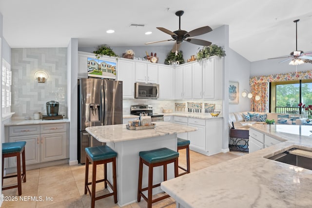 24 Fawn Gully Ln Unit E, Ponte Vedra, FL 32081 - kitchen featuring stainless steel appliances, a ceiling fan, vaulted ceiling, a kitchen breakfast bar, and decorative backsplash