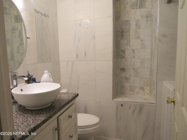 bathroom with vanity, backsplash, toilet, and tile walls