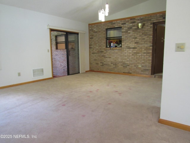 unfurnished room with baseboards, visible vents, carpet, and brick wall