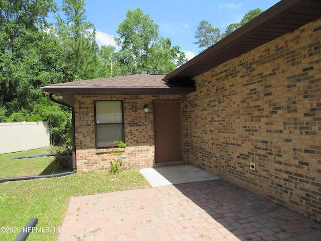 entrance to property with a patio, fence, and brick siding