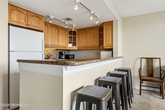 1107 Beach Walker Rd Unit 1107, Amelia Island, FL 32034 - kitchen featuring a kitchen breakfast bar, freestanding refrigerator, brown cabinets, and visible vents
