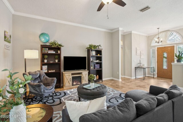 living room featuring ceiling fan, ornamental molding, a textured ceiling, and a glass covered fireplace