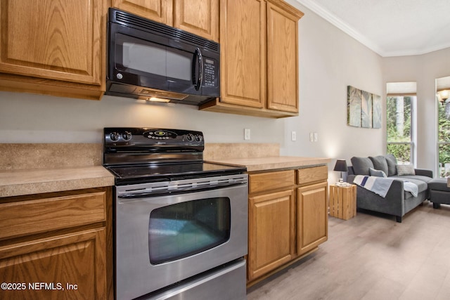kitchen with electric stove, black microwave, light countertops, light wood finished floors, and ornamental molding