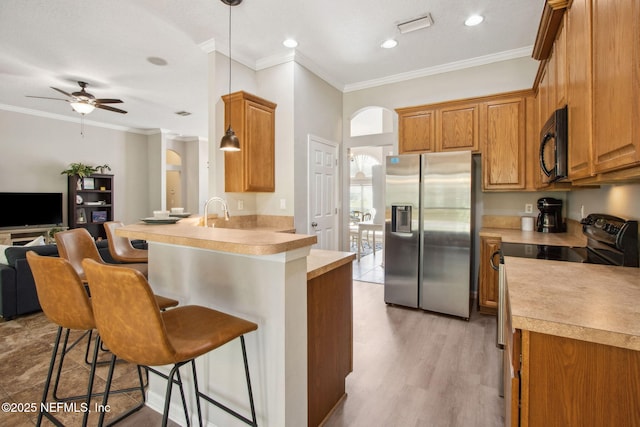 kitchen featuring black appliances, arched walkways, a peninsula, a breakfast bar area, and open floor plan