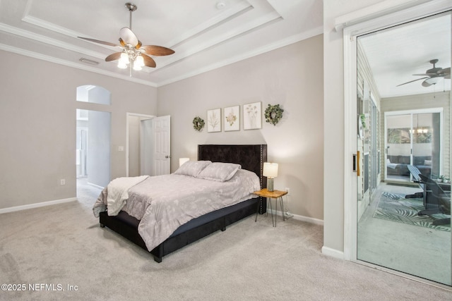 carpeted bedroom with arched walkways, baseboards, ornamental molding, a tray ceiling, and ceiling fan