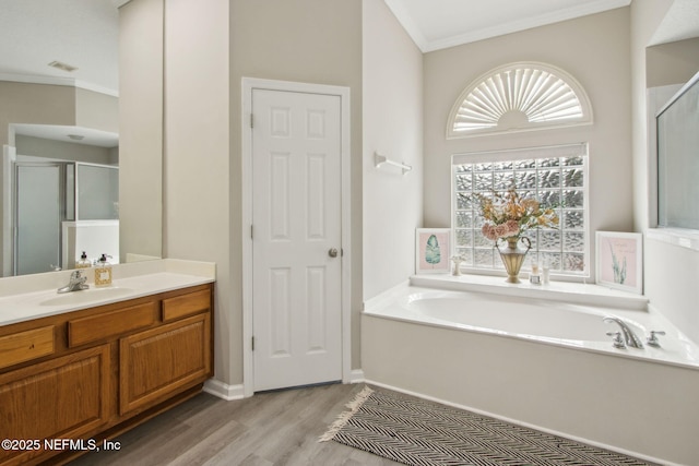 full bathroom featuring crown molding, wood finished floors, vanity, a bath, and a shower stall