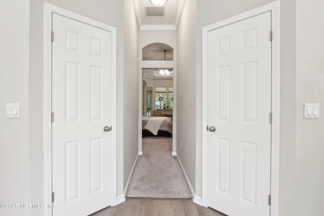 corridor with baseboards, wood finished floors, and ornamental molding
