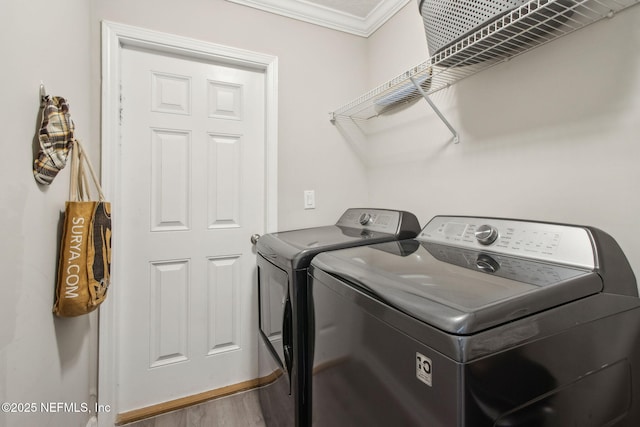 washroom with washing machine and dryer, crown molding, and wood finished floors