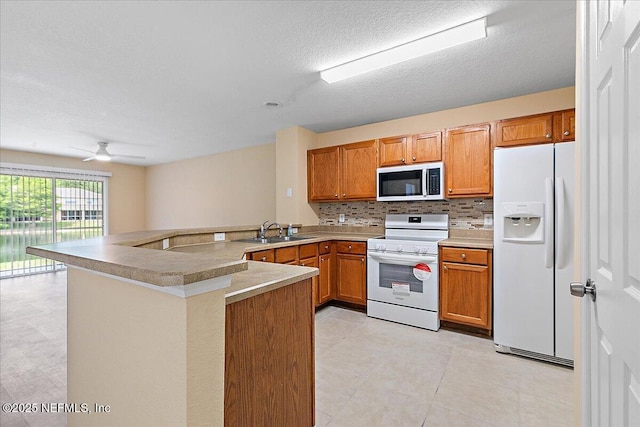 8550 Argyle Business Loop Unit 407, Jacksonville, FL 32244 - kitchen with white appliances, a sink, a peninsula, decorative backsplash, and brown cabinets