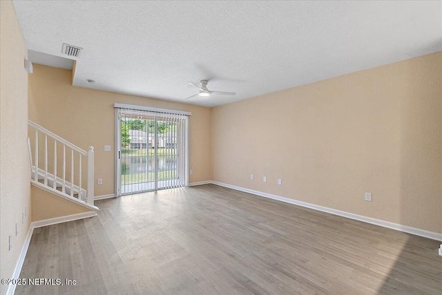8550 Argyle Business Loop Unit 407, Jacksonville, FL 32244 - unfurnished living room featuring a ceiling fan, wood finished floors, stairs, baseboards, and a textured ceiling