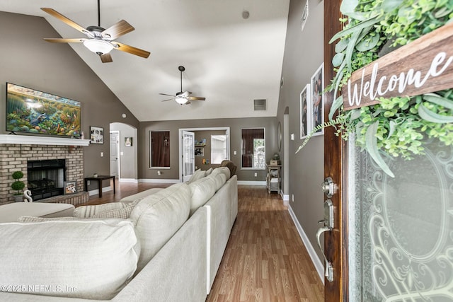 living area with a ceiling fan, wood finished floors, and high vaulted ceiling