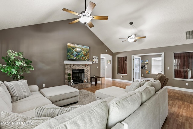 living room featuring dark wood finished floors, high vaulted ceiling, a ceiling fan, and arched walkways
