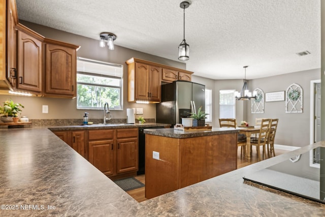 kitchen with stainless steel fridge, dark countertops, visible vents, and a wealth of natural light