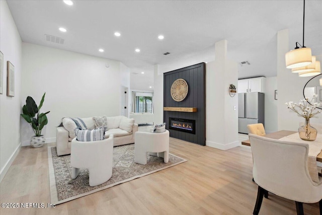 living area with visible vents, light wood-style floors, baseboards, recessed lighting, and a large fireplace