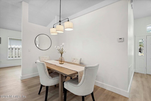 dining room featuring baseboards, vaulted ceiling, and light wood finished floors