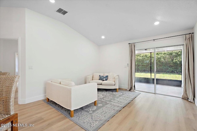 living area featuring baseboards, visible vents, lofted ceiling, and light wood-type flooring