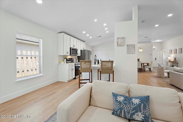 living room featuring recessed lighting, light wood finished floors, and baseboards