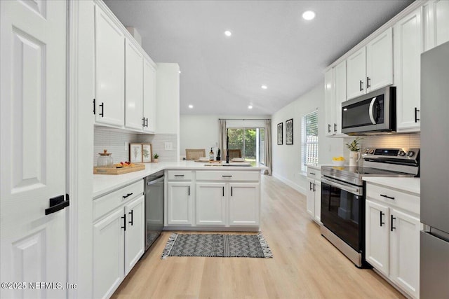 kitchen featuring backsplash, a peninsula, appliances with stainless steel finishes, and light wood-type flooring