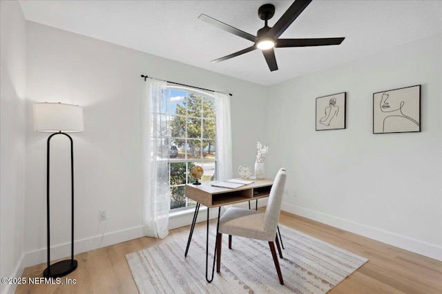 office area featuring a healthy amount of sunlight, baseboards, ceiling fan, and light wood-style flooring