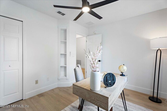 home office featuring visible vents, a ceiling fan, light wood-style floors, and baseboards