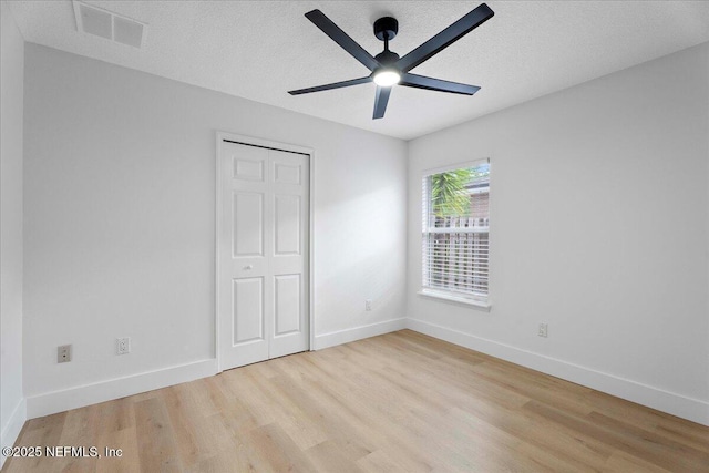 unfurnished bedroom with baseboards, visible vents, light wood-style flooring, and a closet