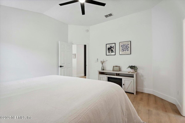 bedroom featuring a ceiling fan, visible vents, baseboards, light wood finished floors, and lofted ceiling