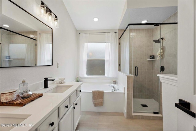 full bathroom with double vanity, a garden tub, a stall shower, a sink, and recessed lighting