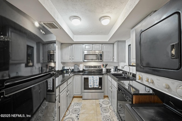 1830 Sevilla Blvd Unit 208, Atlantic Beach, FL 32233 - kitchen with appliances with stainless steel finishes, a sink, stacked washing machine and dryer, a raised ceiling, and a textured ceiling