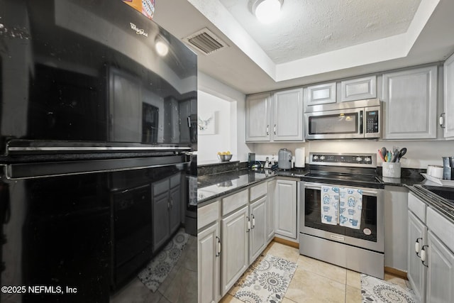 1830 Sevilla Blvd Unit 208, Atlantic Beach, FL 32233 - kitchen with appliances with stainless steel finishes, a raised ceiling, light tile patterned floors, a textured ceiling, and dark stone countertops
