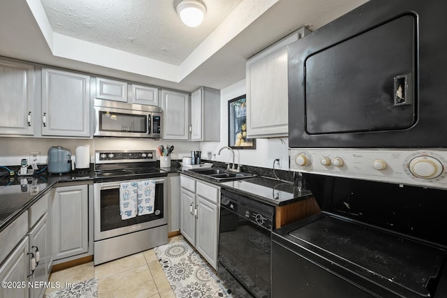1830 Sevilla Blvd Unit 208, Atlantic Beach, FL 32233 - kitchen featuring stainless steel appliances, a sink, stacked washer / drying machine, a tray ceiling, and light tile patterned floors
