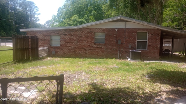 view of side of property featuring brick siding, a lawn, fence, and central air condition unit