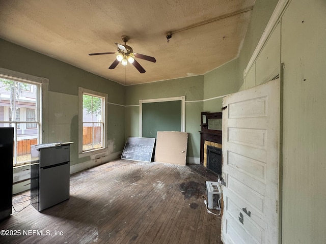 unfurnished living room featuring ceiling fan, a fireplace, an AC wall unit, and hardwood / wood-style floors