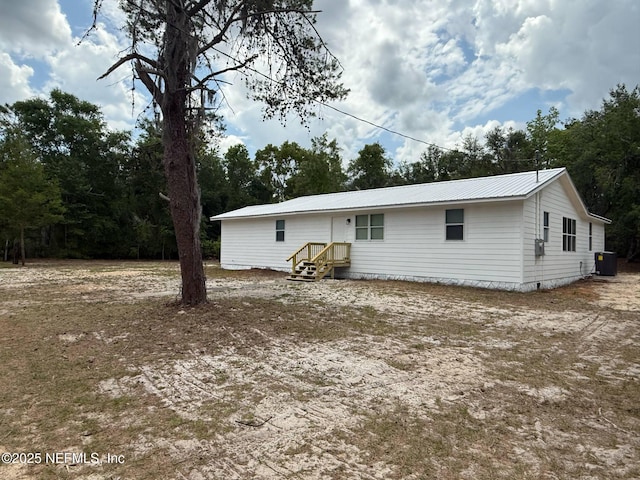 back of property featuring central AC and metal roof