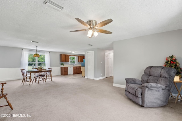 sitting room featuring visible vents, baseboards, ceiling fan, light colored carpet, and a textured ceiling