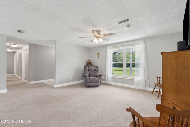 sitting room featuring light carpet, a ceiling fan, a textured ceiling, and visible vents