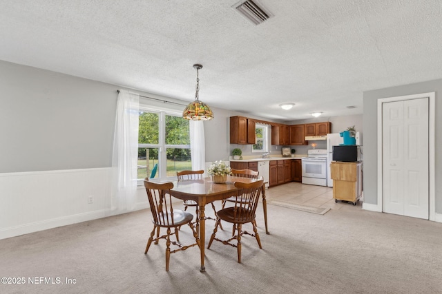 dining area featuring visible vents, a textured ceiling, baseboards, and light colored carpet