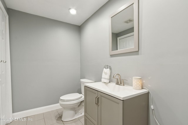 half bathroom featuring toilet, baseboards, visible vents, and vanity