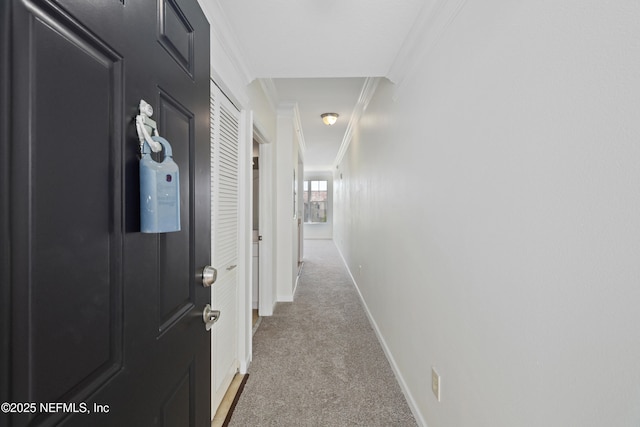hallway with crown molding, baseboards, and light colored carpet